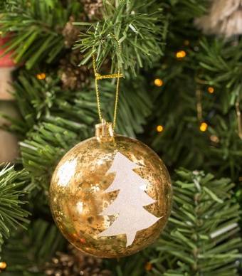 Bola de Natal dourada com desenho de uma árvore branca pendurada numa árvore de natal verde